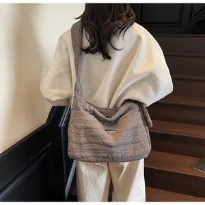 Detailed wave-quilted pattern on a taupe oversized tote bag with a wide shoulder strap