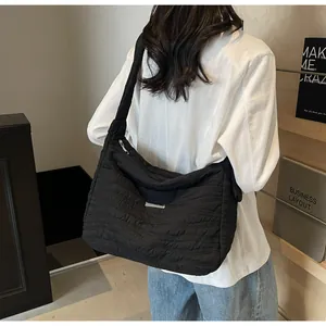 Détail d'un grand sac cabas matelassé noir porté à l'épaule par un mannequin en intérieur