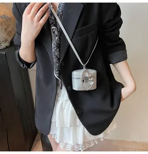 Mini silver cross-body bag with heart pendant chain shown on a fashion model
