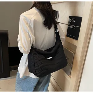 Détail d'un sac à bandoulière matelassé noir avec motif de vagues et sangle réglable