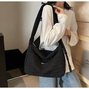 Détail du sac bandoulière noir matelassé avec texture ondulée et large sangle