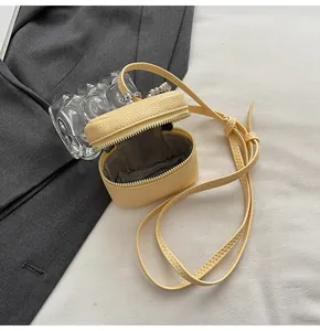 Close-up of pale yellow crossbody bag with litchi texture and silver ball detail