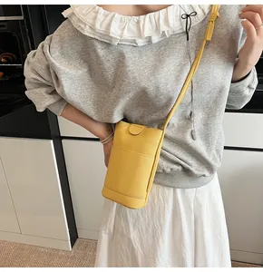 Close-up of bright yellow litchi texture leather phone bag worn as a crossbody accessory