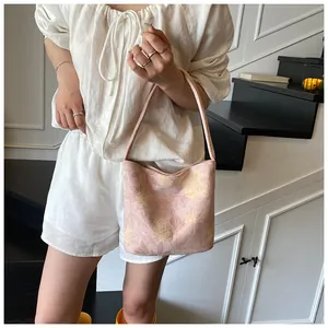 Detail of pink floral canvas bucket bag with wide strap on model in casual summer outfit