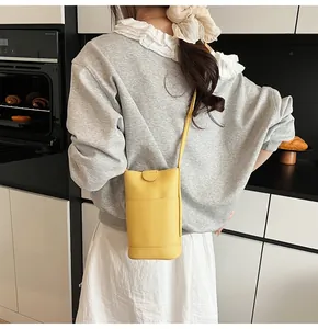 Detail of yellow lychee texture crossbody phone bag with front pocket and magnetic closure