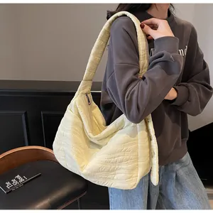 Détail de la texture matelassée ondulée et de la large bandoulière du sac crème