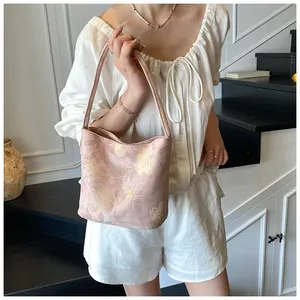 Detail of floral bucket bag with wide strap worn by model in casual white outfit