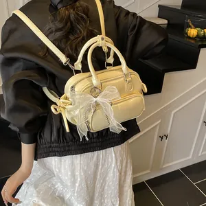 Mochila mini beige chic de cuero sintético para mujer con un lazo y detalle de cadena plata