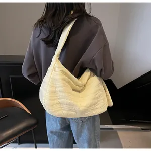 Détail du sac hobo matelassé crème avec coutures ondulées et large bandoulière souple