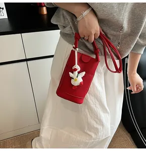 Detail of red lychee pattern crossbody phone bag with a cute white duck charm