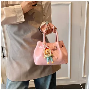 Detail of light pink pleated bucket bag with lychee texture and cute doll pendant