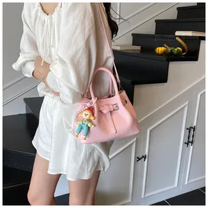 Detailed close-up of pink pleated bucket bag with doll charm and leather texture