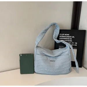 Détail du sac cabas matelassé bleu clair montrant la texture et la plaque métal
