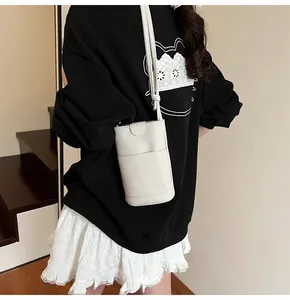 Vertical off-white crossbody phone bag with litchi texture shown on a female model