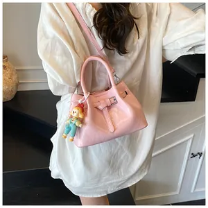 Detail of pink pleated bucket bag featuring a decorative buckle and a cute doll charm