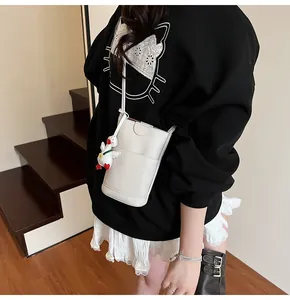 Close-up of white lychee pattern crossbody phone bag with cute duck charm on a model