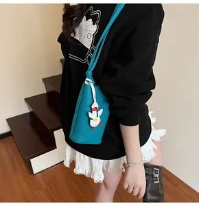Close-up of peacock blue lychee texture bucket bag with cute white duck charm detail