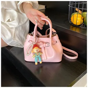 Detail of pink glossy bucket bag with pleated texture, pearl chain and cartoon charm