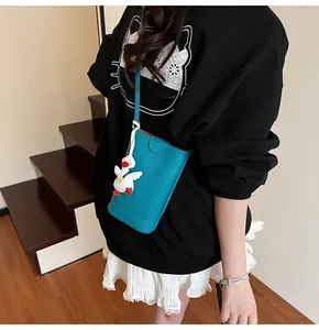 Detail of teal lychee grain leather crossbody bag with a cute white duck charm accessory