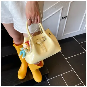 Detail of yellow pleated bucket bag with silver buckle and pearl charm accessory