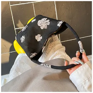 Close-up of black bucket bag featuring delicate white floral embroidery and round handle