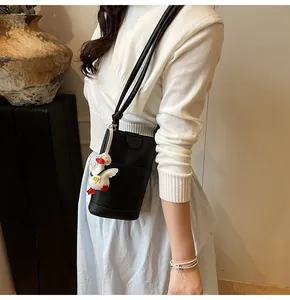 Detail of black litchi grain phone crossbody bag with a cute white duck pendant
