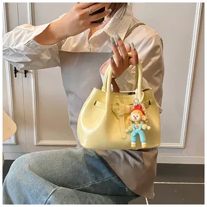 Close-up of cream yellow pleated bucket bag with plush charm and pearl chain detail
