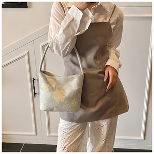 Detailed close-up of grey floral jacquard bucket bag with textured fabric and leaf patterns