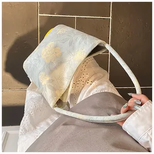 Detail of light blue floral bucket bag with yellow flower patterns and fabric shoulder strap