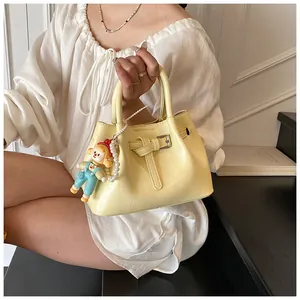 Detail of light yellow ruched bucket bag with pearl chain and cute doll charm