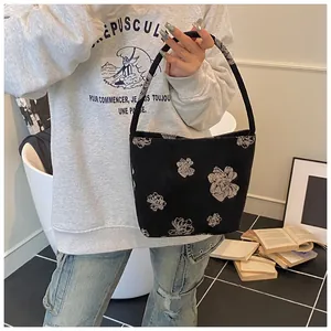 Detail of black and white floral bucket bag with artistic sketch patterns on a canvas texture