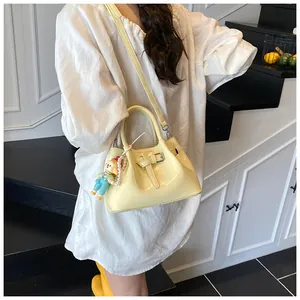 Detail of a creamy yellow pleated bucket bag featuring a circus charm and pearl chain