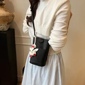 Minimalist black lychee texture crossbody bag with cute duck charm shown on model