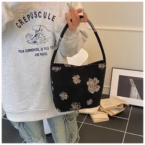 Detail of a black canvas bucket bag featuring elegant beige floral embroidery and single handle