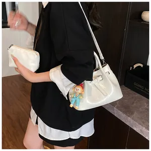 Detail of white glossy bucket bag with matching mini pouch and clown charm accessory