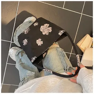Top view of a black bucket bag with white floral sketches and cylindrical handles