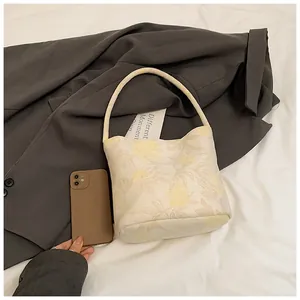 Detail of floral bucket bag showing fabric texture and compact size next to a phone