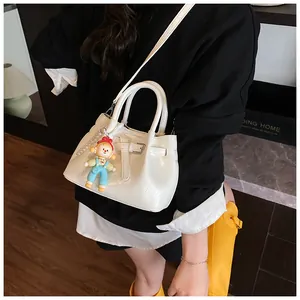 White mini bucket bag with pleated texture and colorful cartoon charm shown in a top view