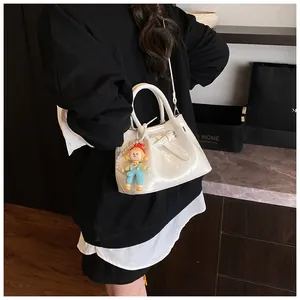 Detail of white patent leather bucket bag with buckle strap and a playful clown charm