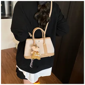 Detail of canvas tote bag with leather trim and brown teddy bear charm pendant