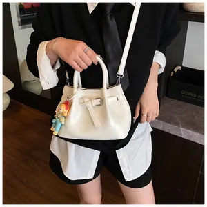 Chic cream pleated bucket bag with long shoulder strap and cute cartoon doll pendant