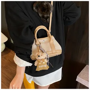 Detail of canvas and leather tote with contrast stitching and plush bear charm