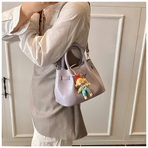 Detail of lavender pleated bucket bag with polished finish and cute cartoon charm accessory