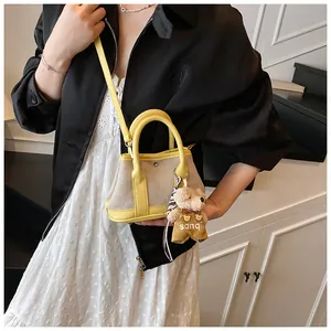 Detail of a contrast color tote bag with two-tone design and a cute plush bear charm