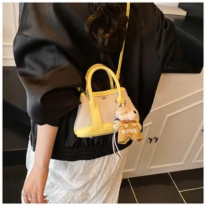 Detail of canvas tote bag with yellow leather trim and cute teddy bear charm