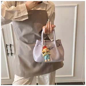 Close-up of light purple pleated bucket bag with pearl chain and cartoon doll pendant