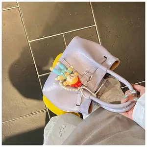 Detail view of lavender bucket bag with pearl chain, cartoon charm, and silver buckle