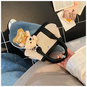Detail of canvas tote bag with contrast leather trim and cute plush bear charm