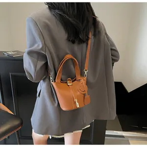Detailed close-up of brown litchi pattern bucket bag with gold metal lock and smiling charm