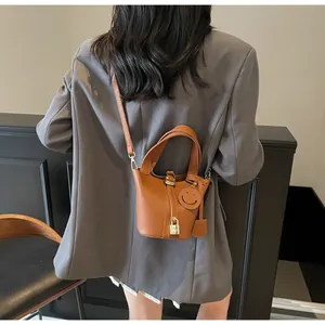 Close-up of brown pebbled leather bucket bag with metallic H-lock and charm detail